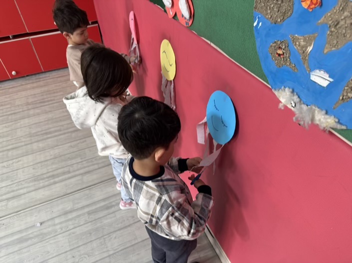 کودکان با کاردستی روی دیوار: فعالیت خلاقانه با قیچی